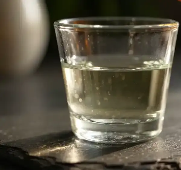 A ribbon of golden glycerin extract curling slowly through a small glass of water